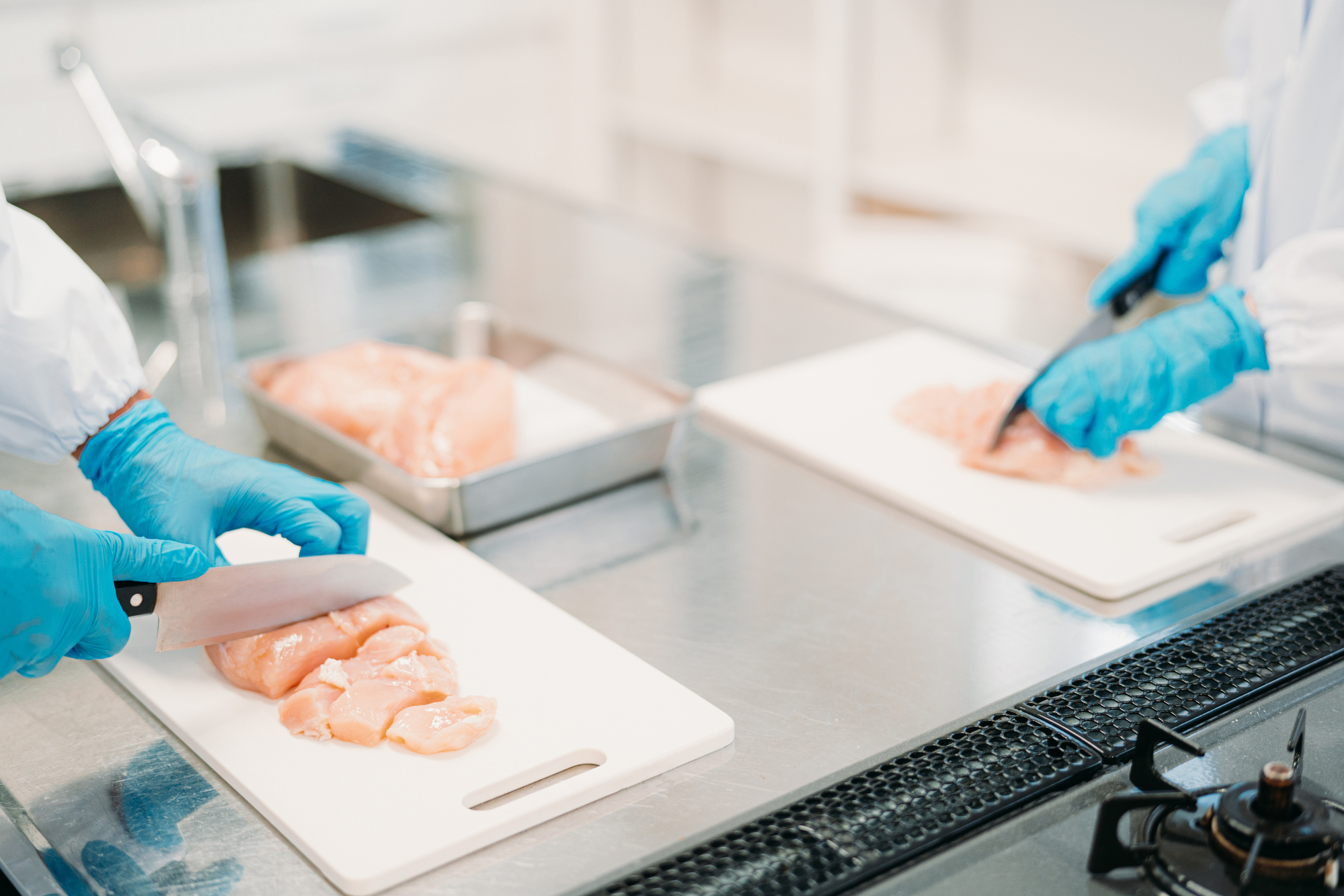 食品用手袋で鶏肉をカットする様子
